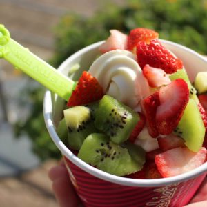A cup of vanilla froyo topped with strawberries and kiwi.