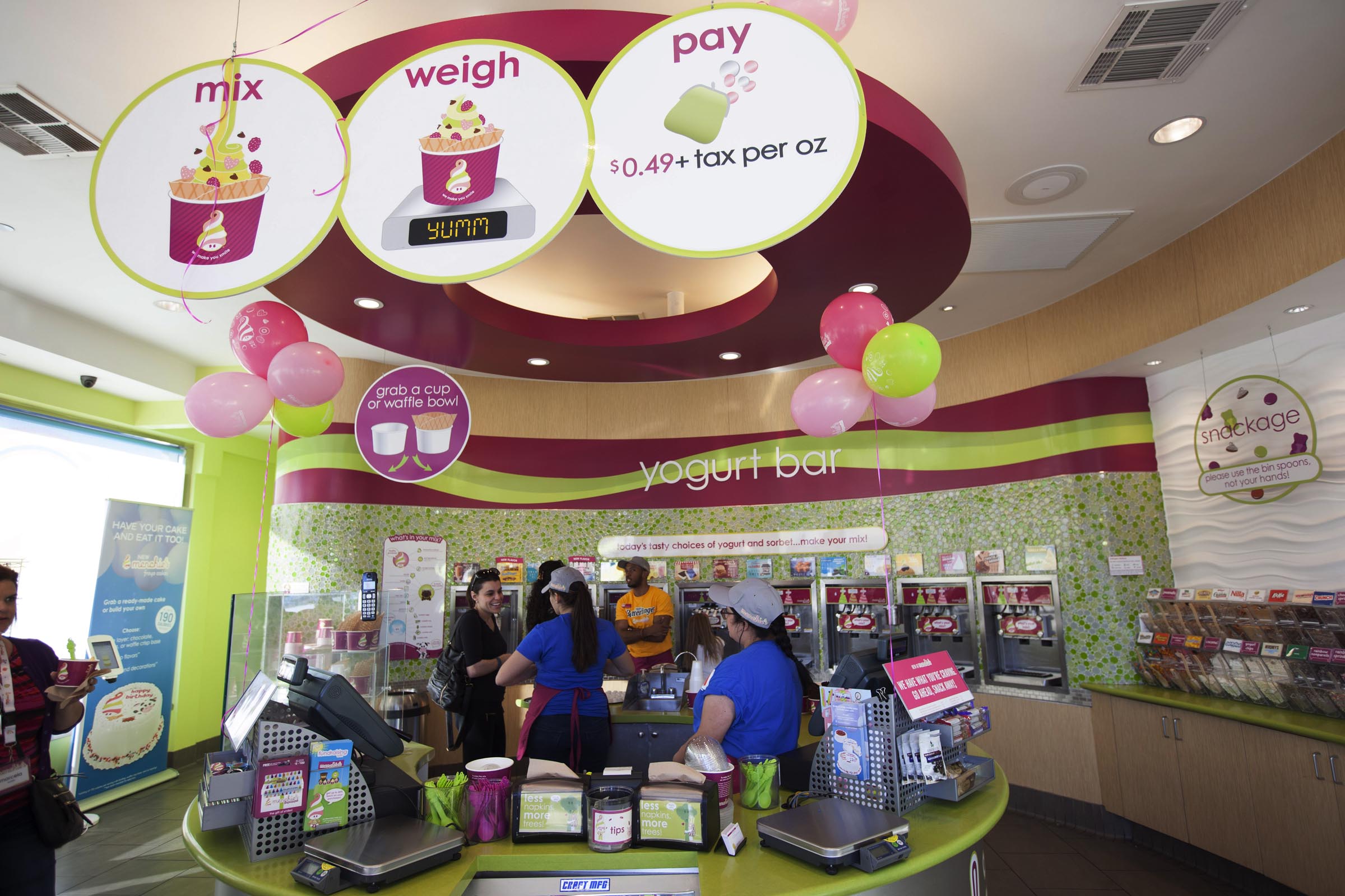 Menchie’s employees help guests weigh and pay for their frozen yogurt.