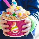 A child holding a cup of Menchie's frozen yogurt