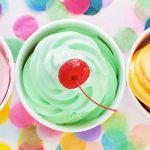 Three cups of frozen yogurt with cherries on top