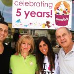 A group in front of a sign that says Celebrating 5 years